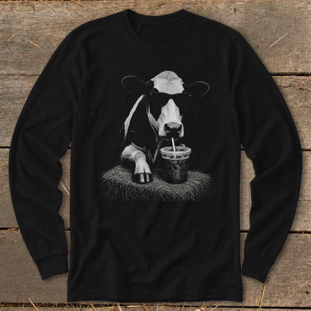Black long-sleeve shirt featuring a cow wearing sunglasses, drinking from a cup on hay.