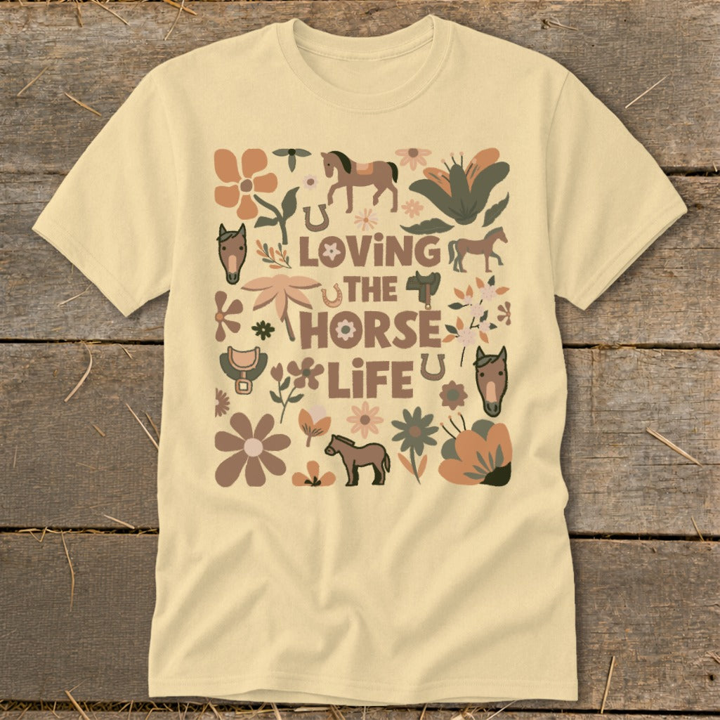 Cream t-shirt with a graphic design of horses, flowers, and text "Loving the Horse Life".