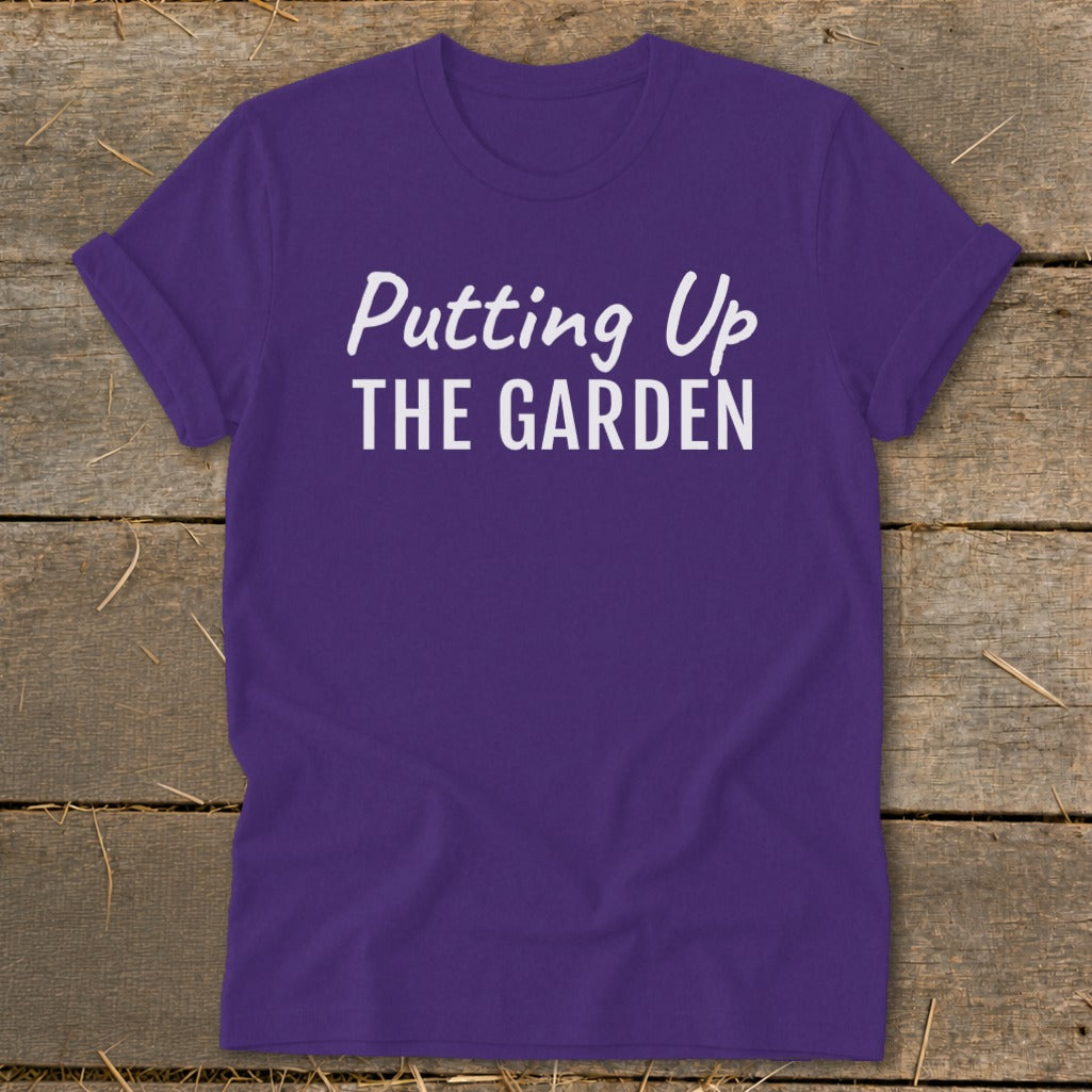 Purple t-shirt with white text that reads "Putting Up THE GARDEN".