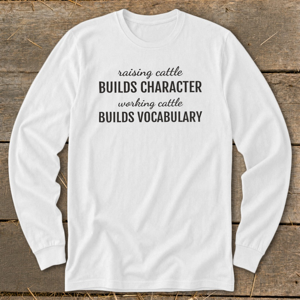 White long sleeve shirt with text "Raising cattle builds character, working cattle builds vocabulary."