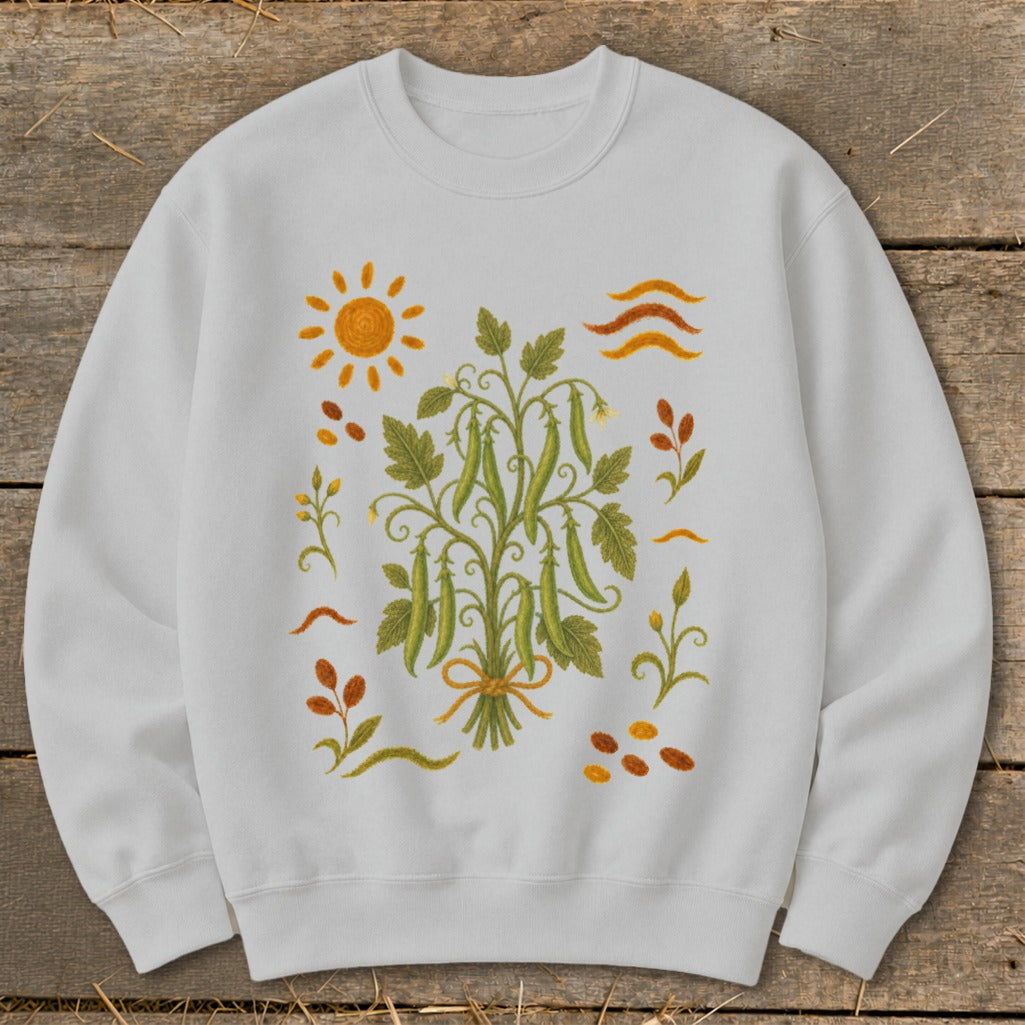 White sweatshirt with a central bouquet of pea pods and surrounding sun, leaves, and scattered beans.
