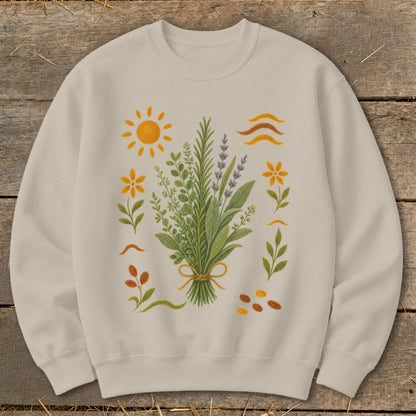 Cream sweatshirt with a botanical illustration of herbs, flowers, sun, and seeds.