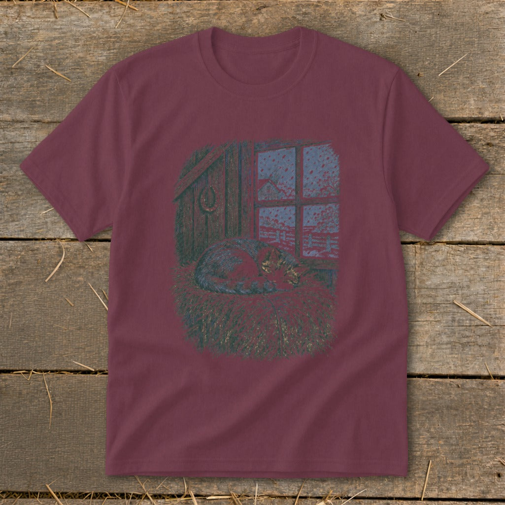T-shirt with graphic of cat sleeping in hay near a window looking out at snow.