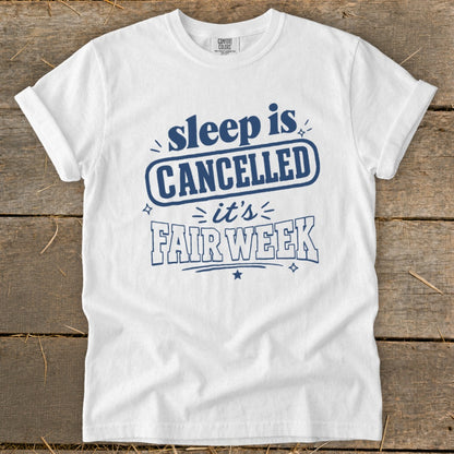 White t-shirt with blue text that reads "sleep is CANCELLED it's FAIR WEEK".