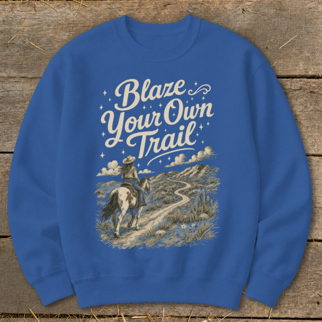 Crewneck sweatshirt with "Blaze Your Own Trail" text and horseback rider in desert landscape.