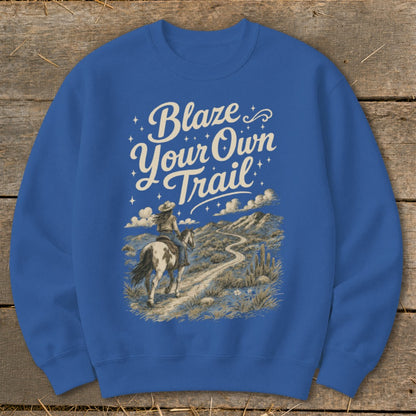 Crewneck sweatshirt with "Blaze Your Own Trail" text and horseback rider in desert landscape.