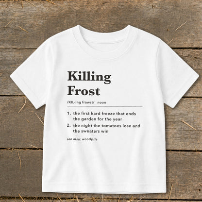 A white t-shirt featuring dictionary-style text that defines Killing Frost laid flat on wooden boards.