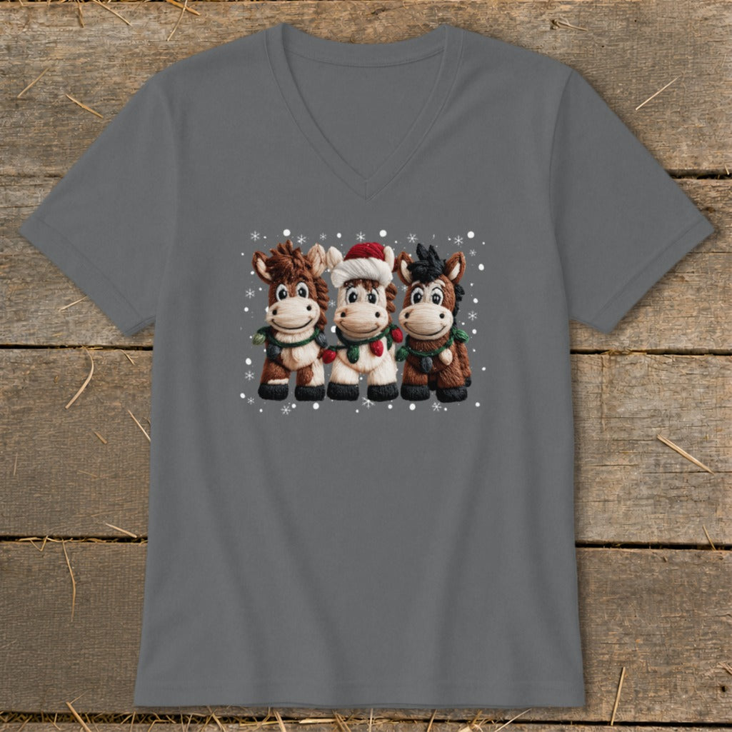 Three cartoon horses wearing festive Christmas attire with falling snowflakes.