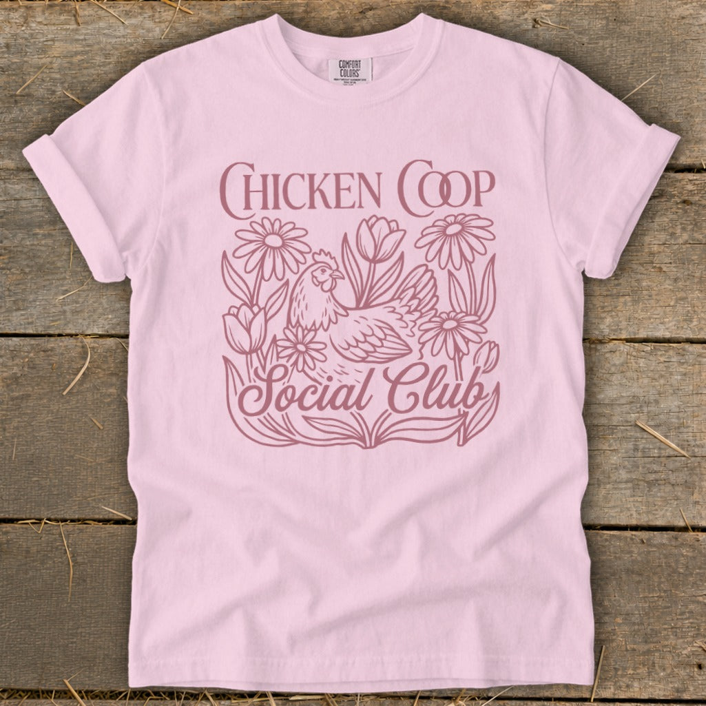 Pink t-shirt with a chicken and flowers graphic that says "CHICKEN COOP Social Club".