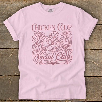 Pink t-shirt with a chicken and flowers graphic that says "CHICKEN COOP Social Club".