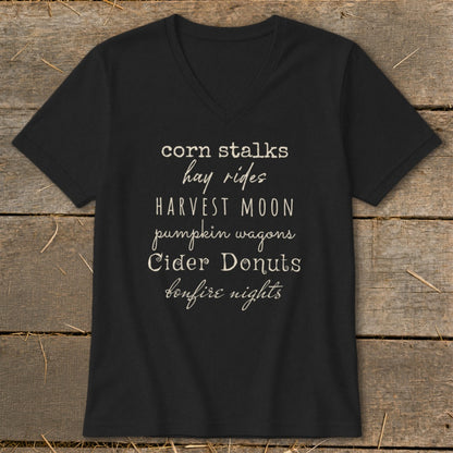 Black V-neck t-shirt with text listing fall activities: corn stalks, hay rides, harvest moon, pumpkin wagons, cider donuts, bonfire nights.