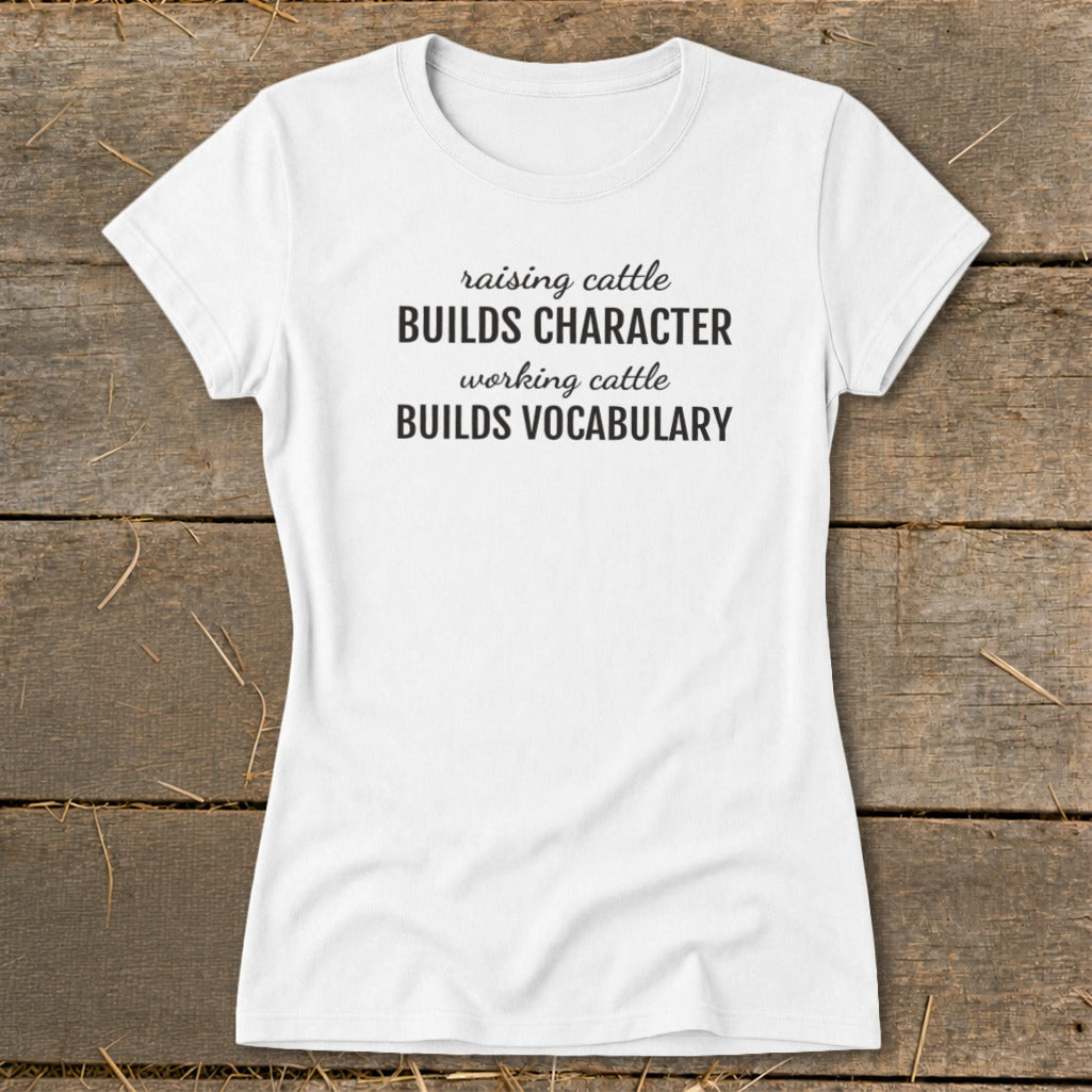 White t-shirt with black text reading "raising cattle BUILDS CHARACTER working cattle BUILDS VOCABULARY."