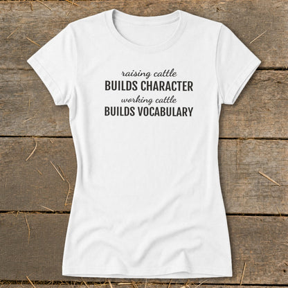 White t-shirt with black text reading "raising cattle BUILDS CHARACTER working cattle BUILDS VOCABULARY."