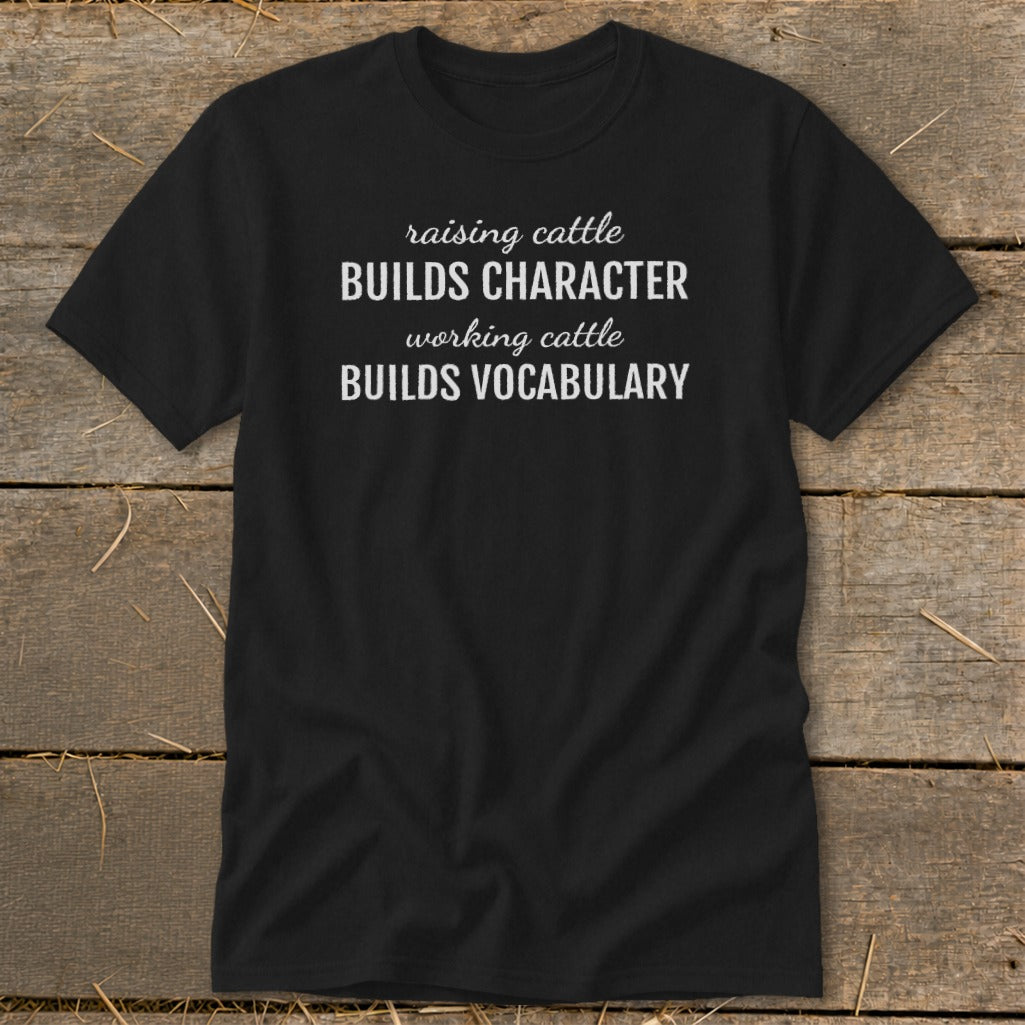 Black t-shirt with white text: "raising cattle BUILDS CHARACTER working cattle BUILDS VOCABULARY".