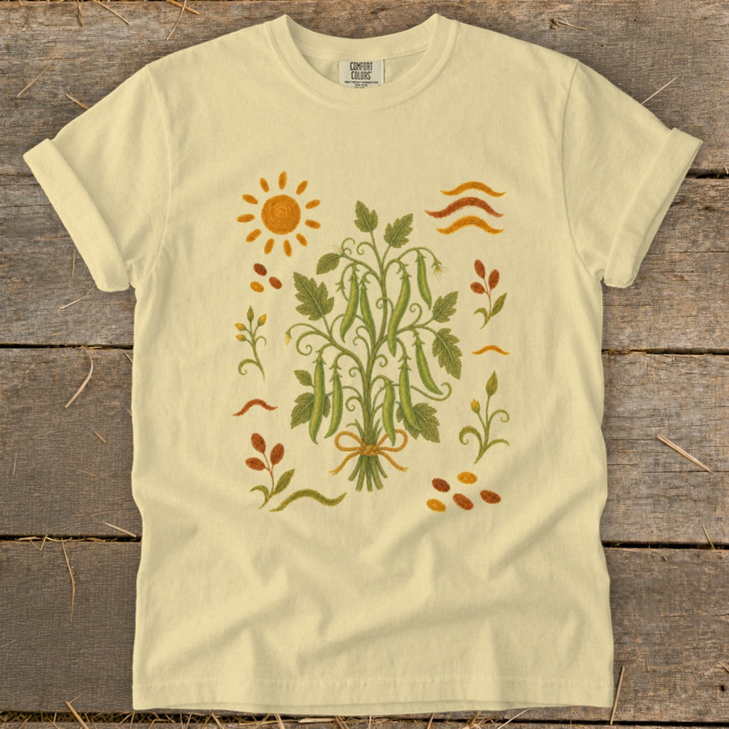 Light yellow t-shirt with a central illustration of a pea pod plant and a sun.