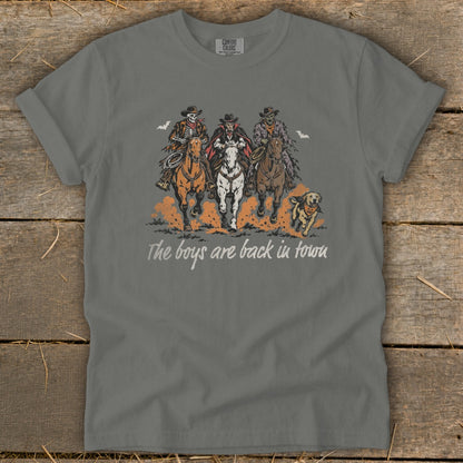 Three characters on horses, a skeleton, a vampire, and a mummy, ride with a dog. Text reads "The boys are back in town."