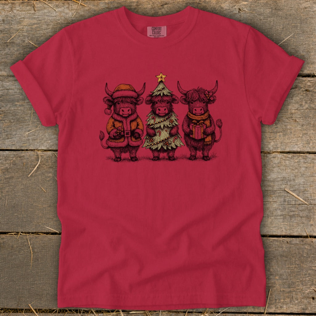 Three Highland cows in festive holiday outfits standing together.