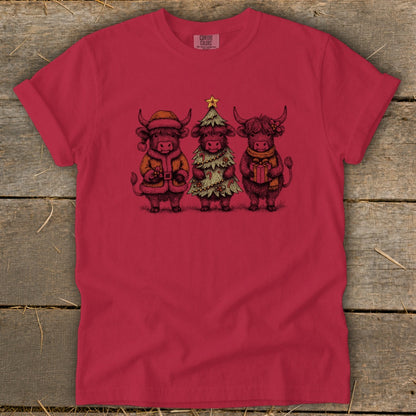 Three Highland cows in festive holiday outfits standing together.