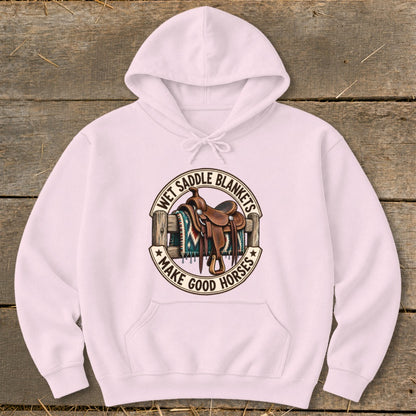 Pink hoodie with circular graphic of a saddle and blanket, saying "Wet Saddle Blankets Make Good Horses".