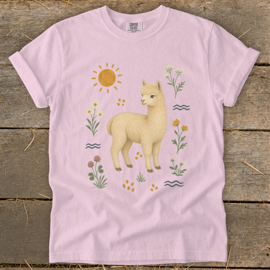 Light pink t-shirt with a cream-colored alpaca illustration surrounded by flowers and sun.