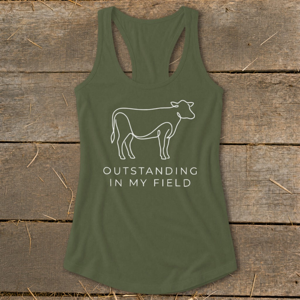 Olive green tank top with white line drawing of a cow and text "OUTSTANDING IN MY FIELD".