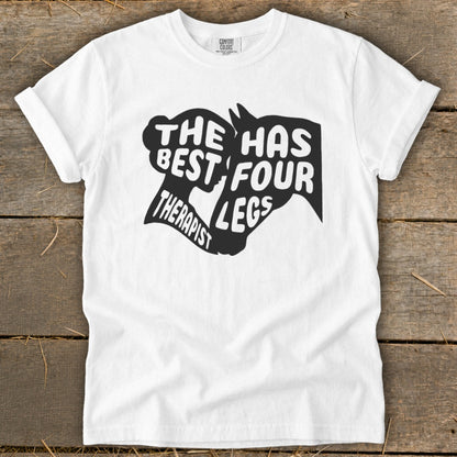 White t-shirt with black graphic text "The Best Therapist Has Four Legs" and horse silhouette.