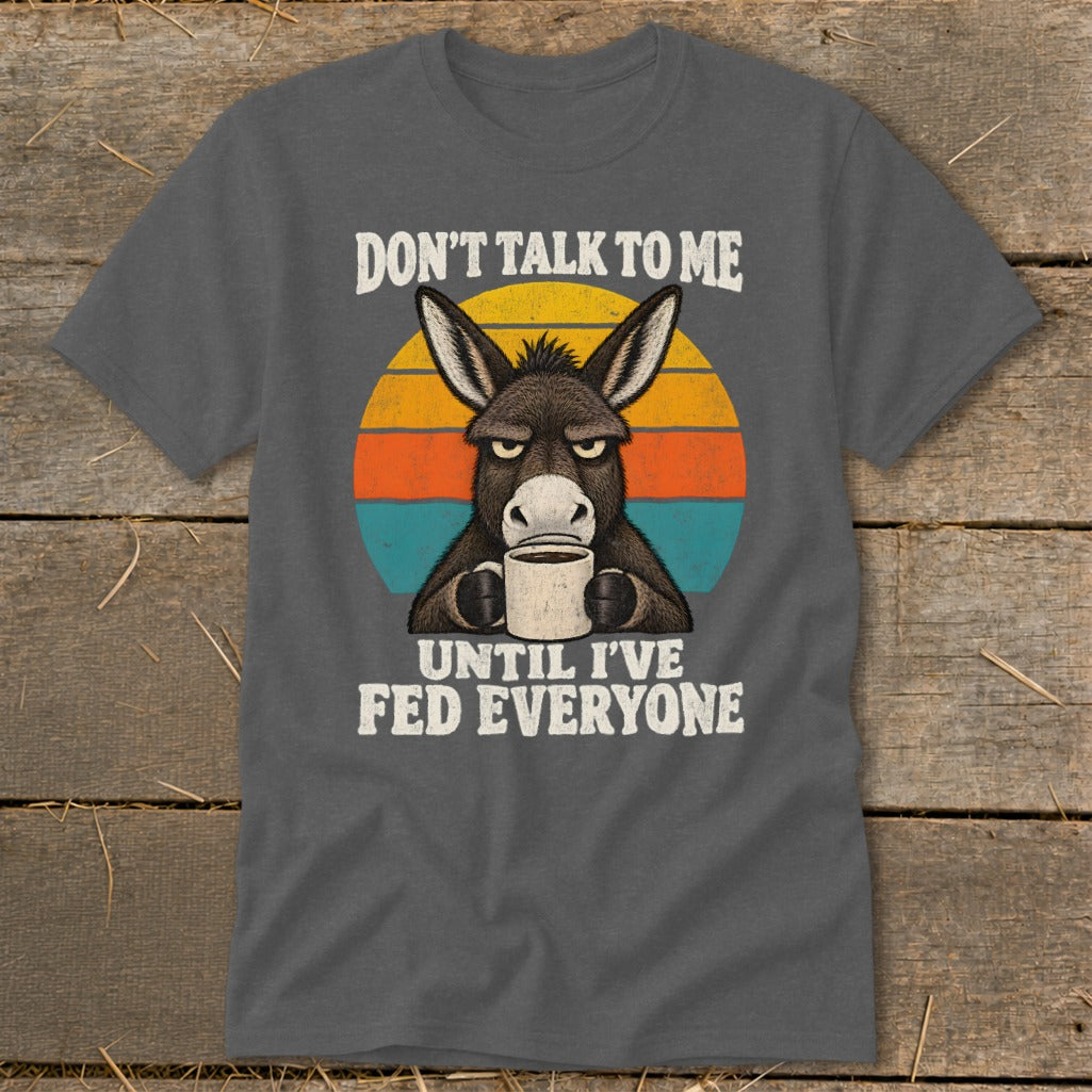 A dark gray t-shirt featuring an angry donkey holding a coffee mug with the text Don't Talk to Me Until I've Fed Everyone.