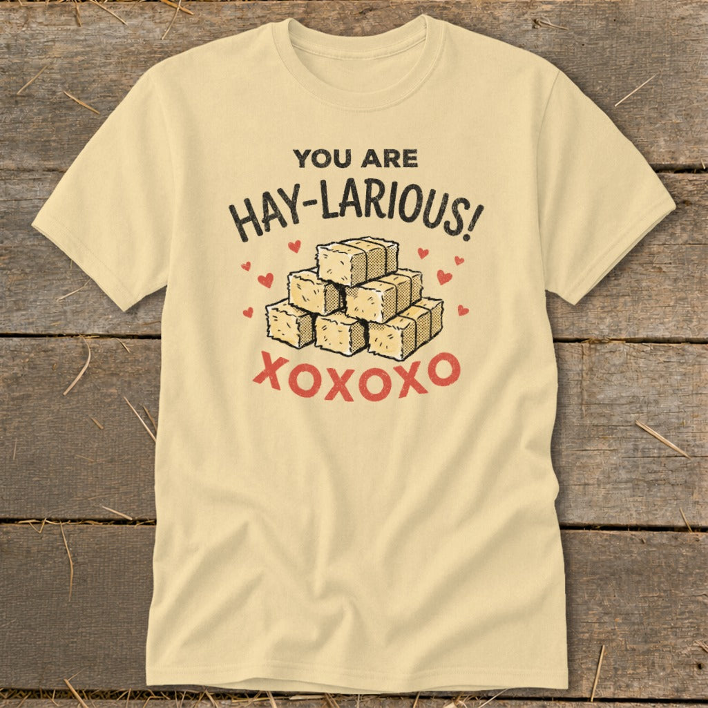 Yellow t-shirt with text "YOU ARE HAY-LARIOUS!" above a pile of hay bales and "XOXOXO".