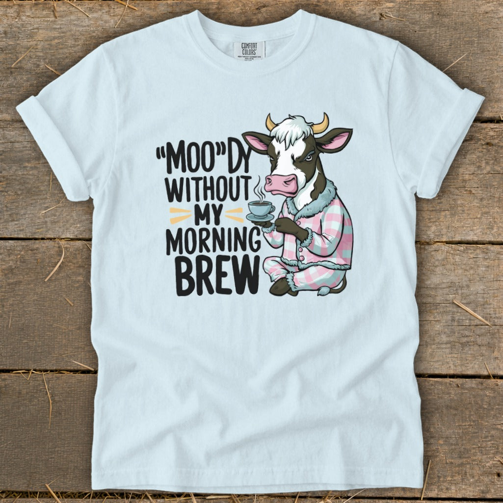 Light blue t-shirt with cow in pajamas holding coffee, reads "Moo'dy Without My Morning Brew."