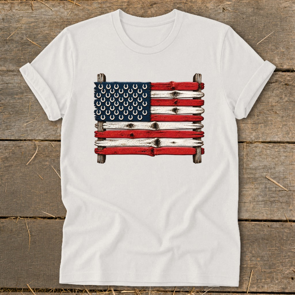 White t-shirt featuring a rustic American flag graphic made of weathered wood planks and horseshoes.