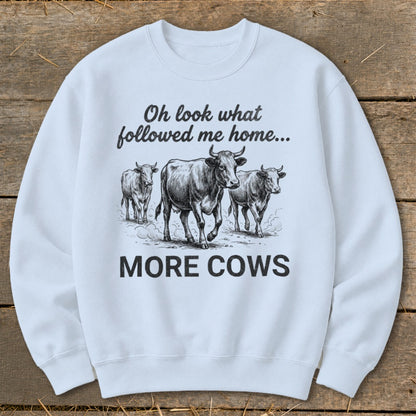 Light blue sweatshirt with a sketch of three cows and text "Oh look what followed me home... MORE COWS".
