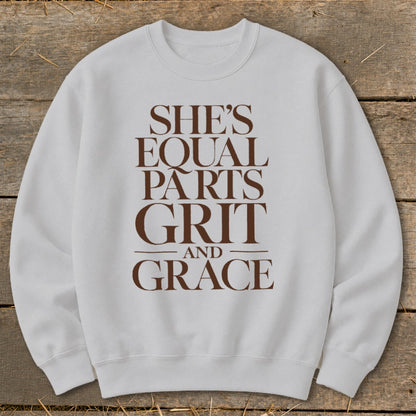 Light grey sweatshirt with brown text reading "SHE'S EQUAL PARTS GRIT AND GRACE".