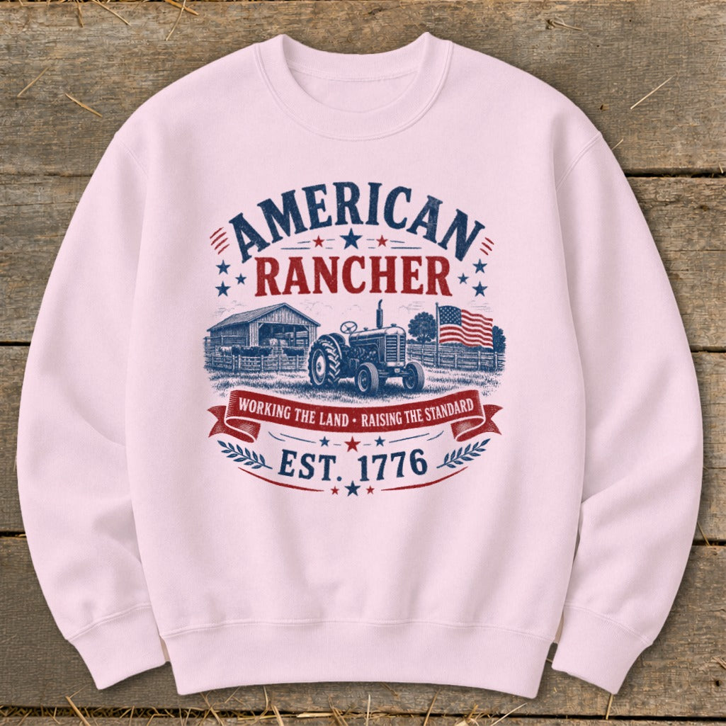 Pink sweatshirt with "American Rancher" graphic featuring tractor, barn, and American flag.
