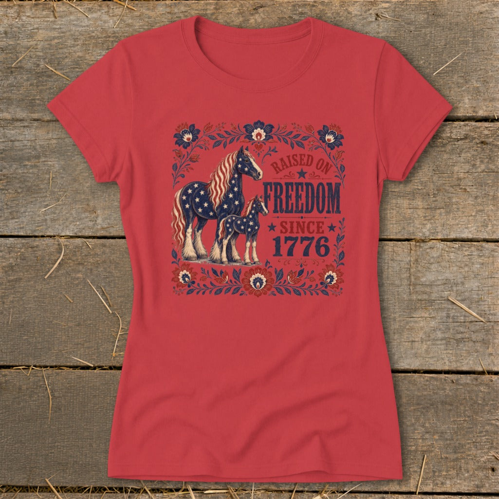 Red t-shirt with graphic of two horses and text "Raised on Freedom Since 1776".