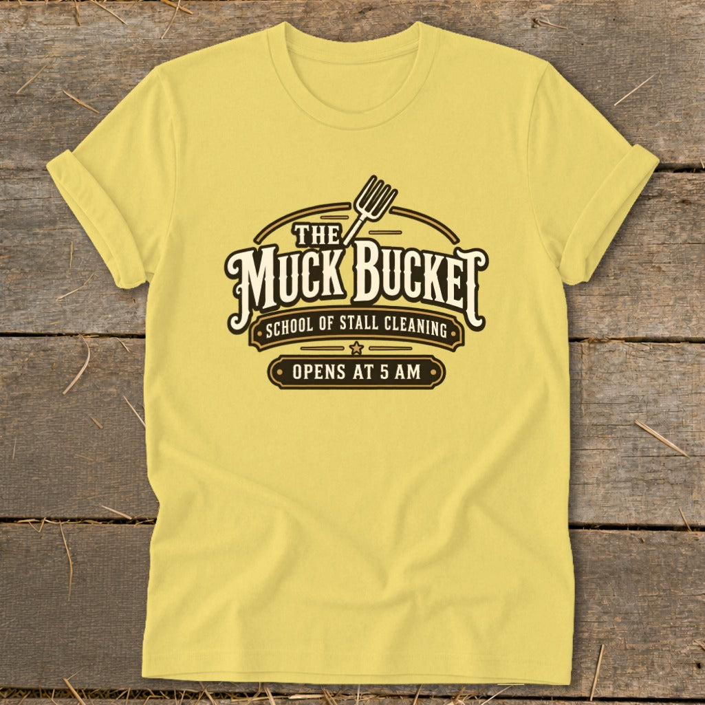 Yellow t-shirt with "The Muck Bucket School of Stall Cleaning Opens at 5 AM" logo.