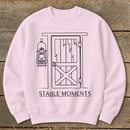 Pink sweatshirt with line drawing of barn door, lantern, and text "STABLE MOMENTS".