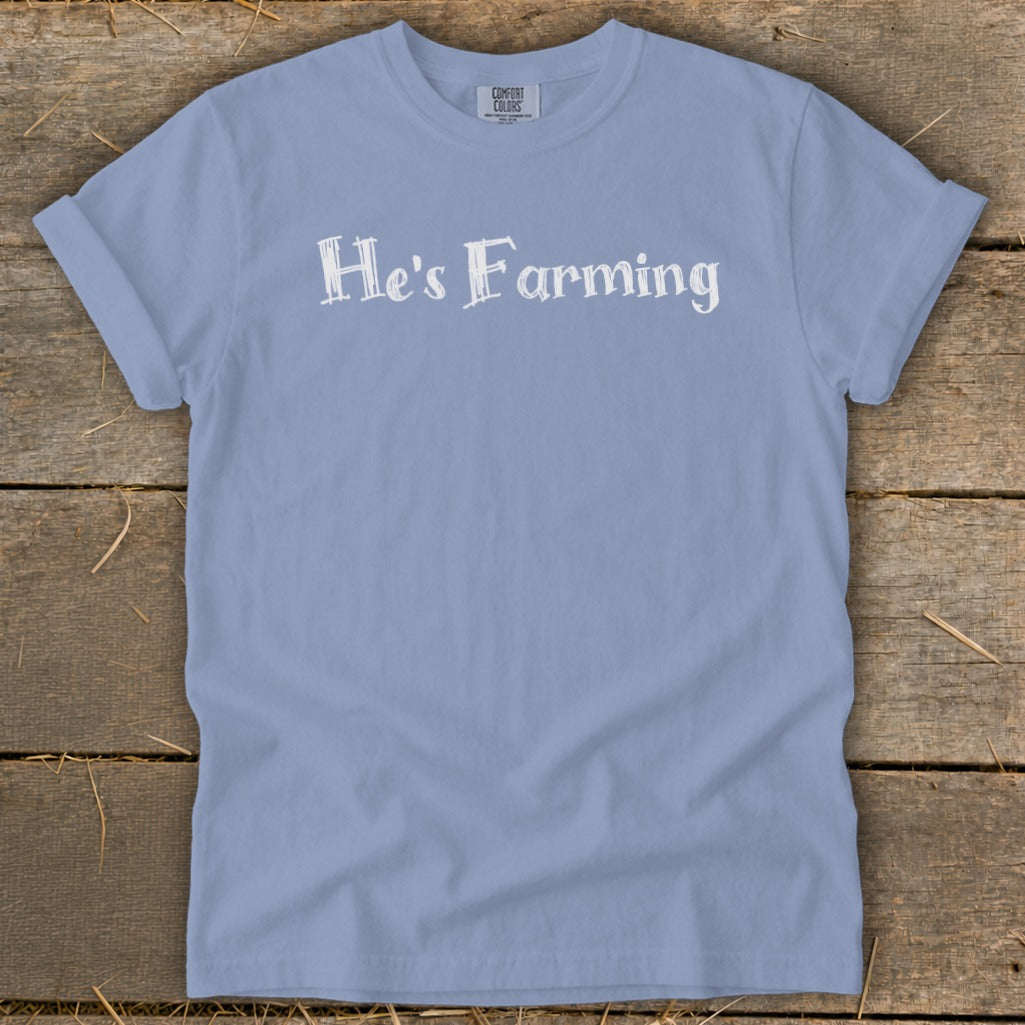 Light blue t-shirt with "He's Farming" text in white lettering.