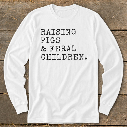 White long-sleeved shirt with black text: Raising Pigs & Feral Children.
