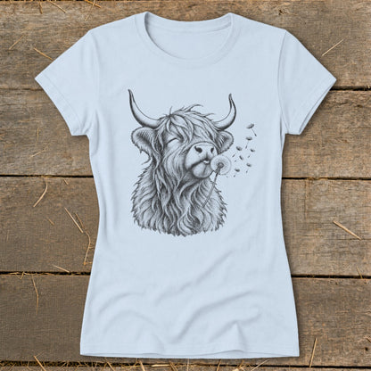 Black and white sketch of a highland cow blowing a dandelion on a light blue t-shirt.