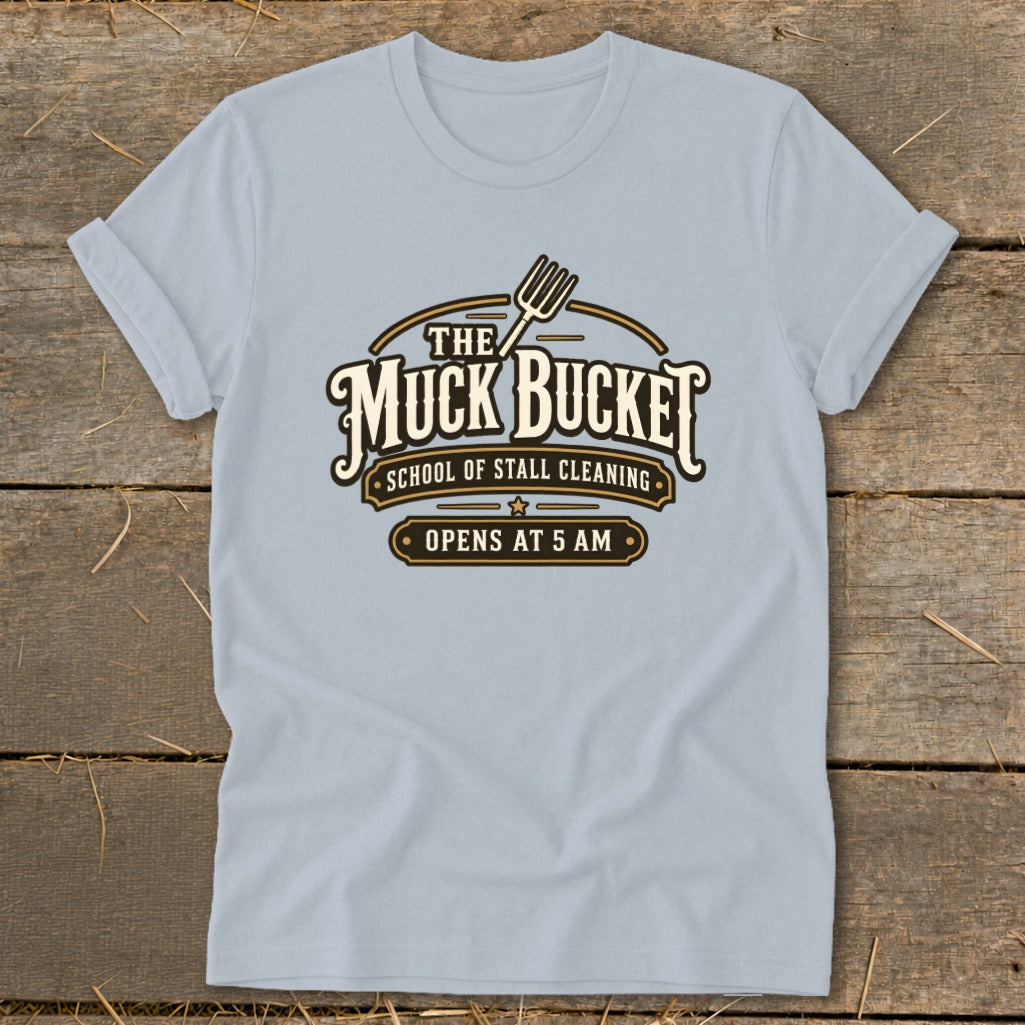 Light blue t-shirt with "The Muck Bucket School of Stall Cleaning" logo.
