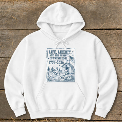 White hoodie with a blue graphic of chickens, a coop, and the text "Life, Liberty, And The Pursuit Of Fresh Eggs".