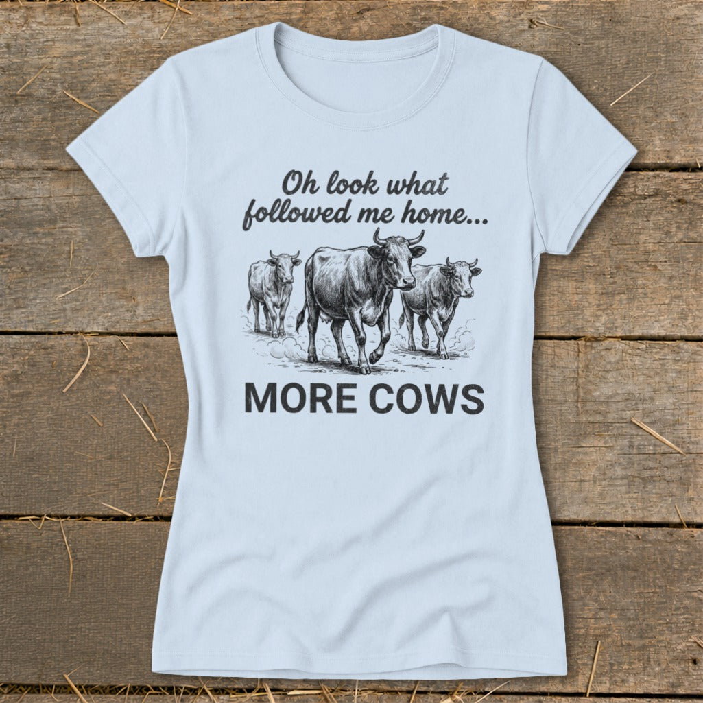 Light blue t-shirt with a drawing of three cows and the text "Oh look what followed me home... MORE COWS".