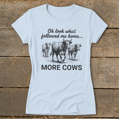 Light blue t-shirt with a drawing of three cows and the text "Oh look what followed me home... MORE COWS".