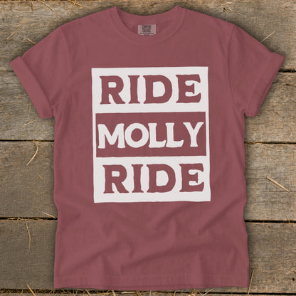 A dusty rose t-shirt features a white rectangular graphic on the chest with the text "RIDE MOLLY RIDE" in bold, distressed block lettering.