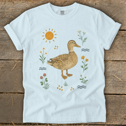 Light blue t-shirt with a duck and floral design, featuring sun and water elements.