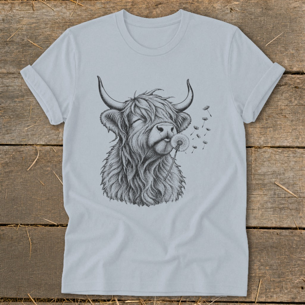 Highland cow blowing dandelion seeds on a light blue t-shirt.