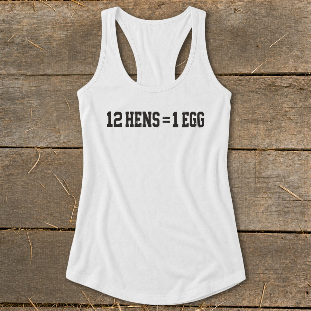 A white racerback tank top with the black text 12 HENS = 1 EGG laid flat on a wooden background.