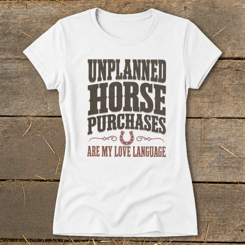 White t-shirt with "Unplanned Horse Purchases Are My Love Language" text and horseshoe graphic.