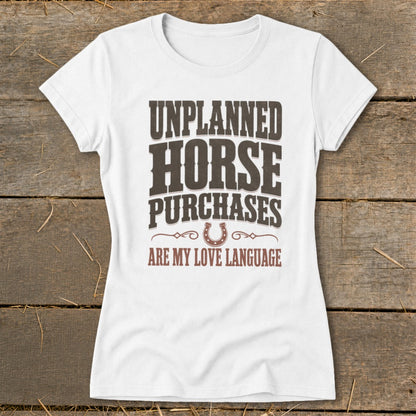 White t-shirt with "Unplanned Horse Purchases Are My Love Language" text and horseshoe graphic.