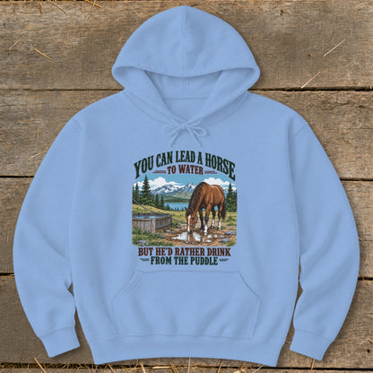 A light blue hooded sweatshirt features a graphic of a horse drinking from a puddle with text above and below.